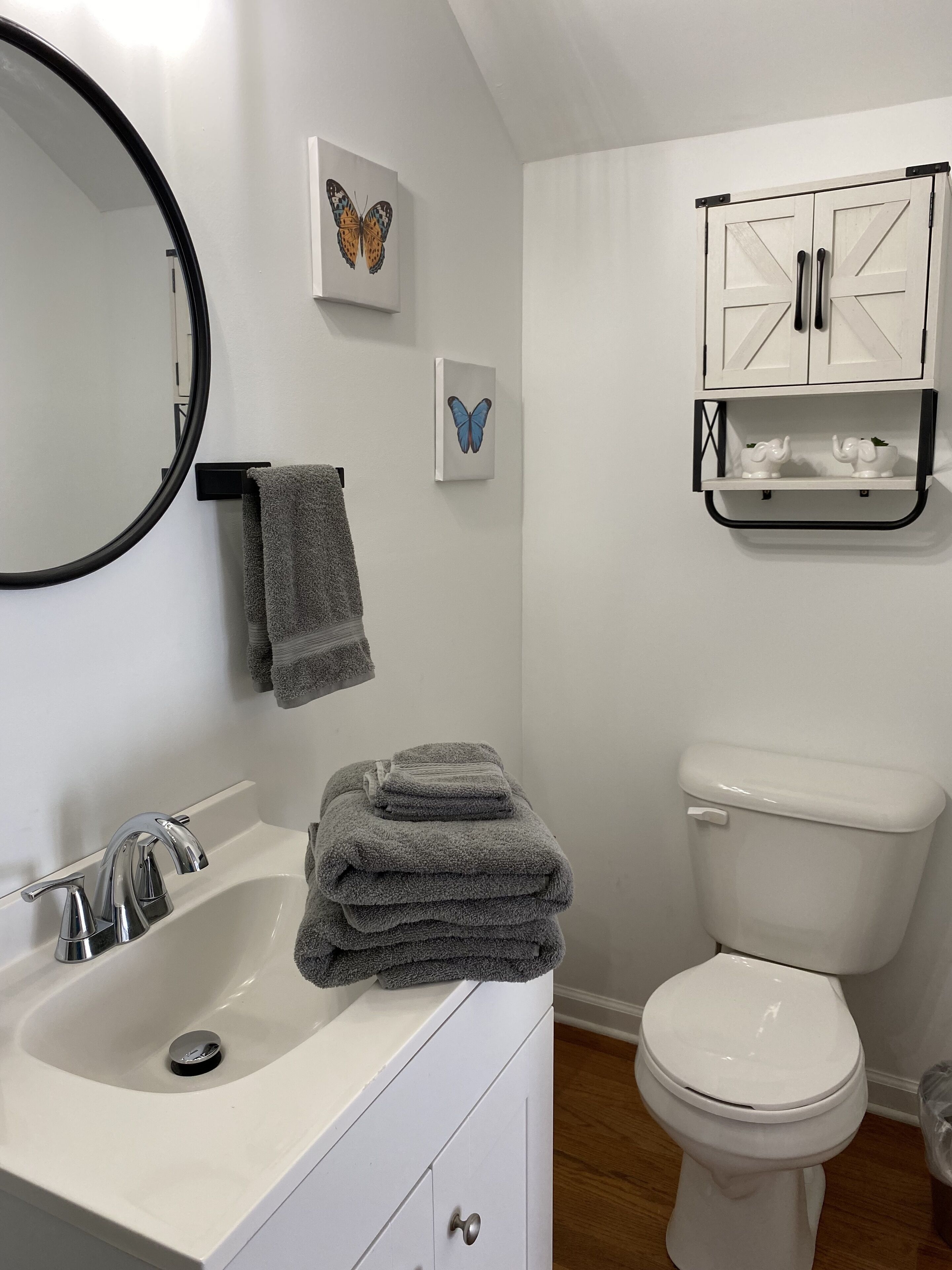 Une salle de bain avec un lavabo blanc, des toilettes et un meuble au-dessus des toilettes.