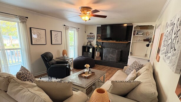 A living room with a sofa set, a coffee table, a fireplace, and a television. - Charming Cape Cod Style Home-Masters Rental (Augusta)