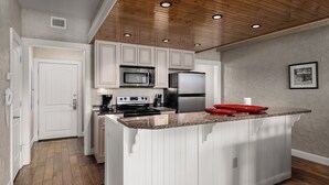 A kitchen with white cabinetry, a stainless steel refrigerator, a microwave, and a stove.