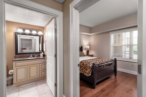 A bedroom with a bed, a nightstand, a lamp, and a window with blinds. - Luxury Condo in Pigeon Forge (Pigeon Forge)