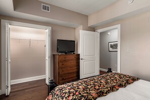 A bedroom with a bed, a dresser, a television on top of the dresser, and a door leading to another room. - Luxury Condo in Pigeon Forge (Pigeon Forge)
