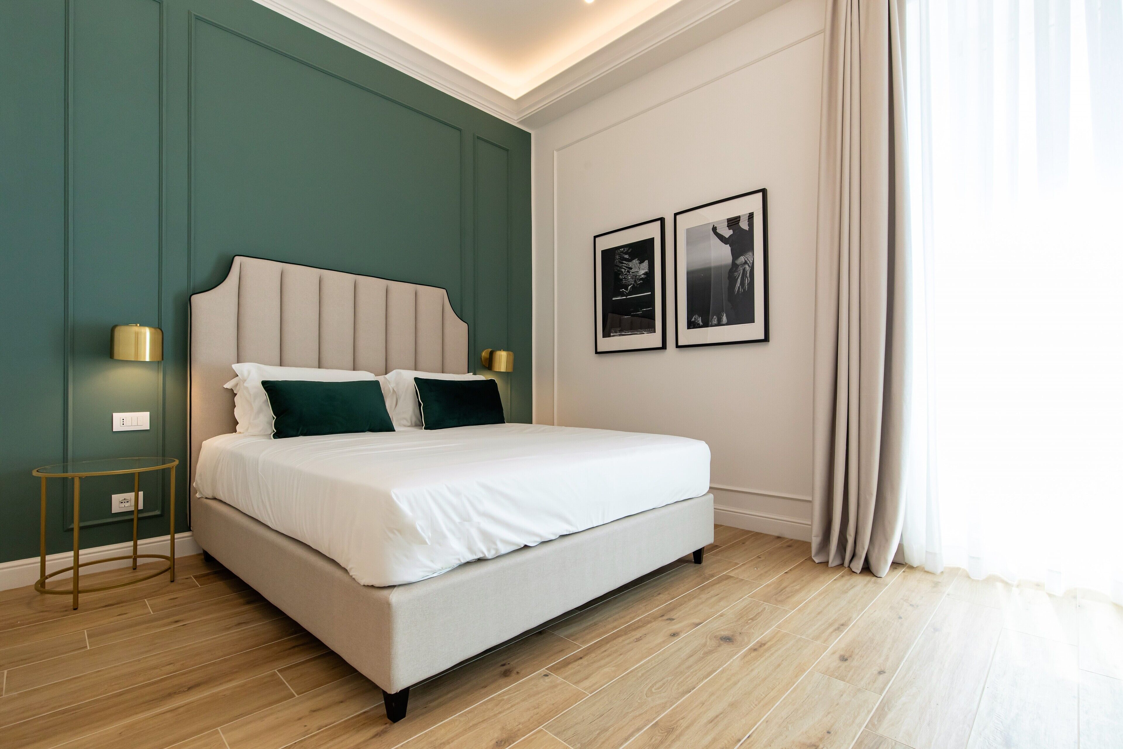 A modern bedroom with a large bed, two bedside lamps, and two framed pictures on the wall.