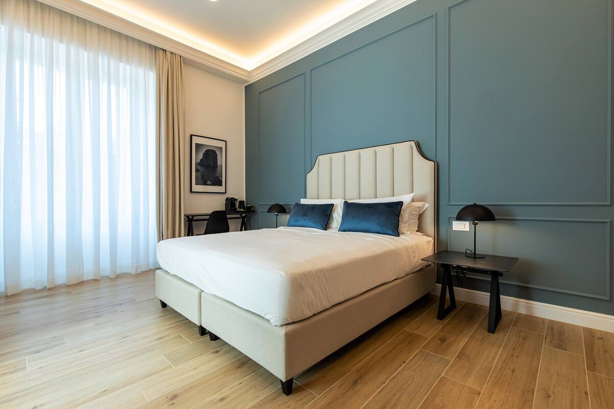 A modern bedroom with a large bed, a desk, and a chair.