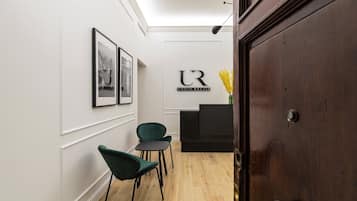 A reception area with a dark reception desk, framed photographs on the wall, and two green chairs.