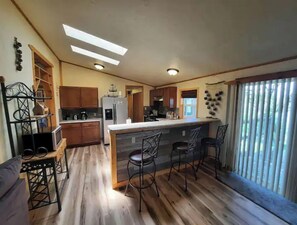 A kitchen with wooden flooring, a central island with bar stools, and a refrigerator.