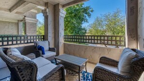 A covered outdoor seating area with wicker furniture and a view of trees. - North Scottsdale-Luxurious, newly-renovated condo, great location in Kierland (Scottsdale)