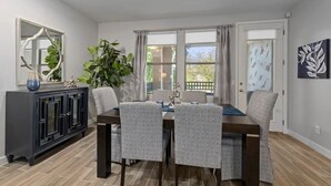 A dining area with a dark wooden table and patterned chairs, a black cabinet with glass doors, and a large plant. - North Scottsdale-Luxurious, newly-renovated condo, great location in Kierland (Scottsdale)