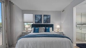 A bedroom with a large bed, two bedside tables with lamps, a window with curtains, and two abstract wall art pieces. - North Scottsdale-Luxurious, newly-renovated condo, great location in Kierland (Scottsdale)