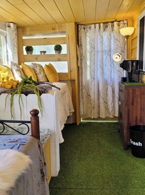 Une pièce confortable avec un lit, une petite table et une lampe, ainsi qu’une poubelle.