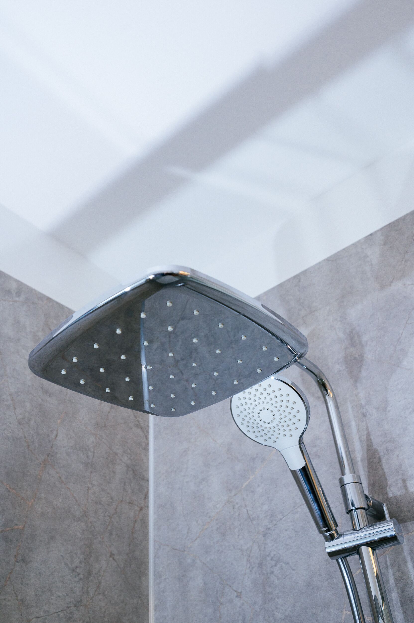 A showerhead with a square design and multiple nozzles, mounted on a chrome fixture.