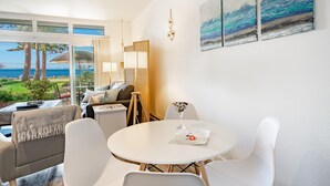 A modern living room with a view of the sea, a round dining table, and a sofa.