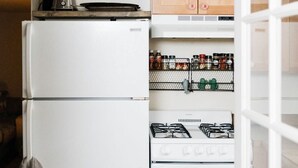 Pieni, käytännöllinen keittiö, jossa on valkoinen jääkaappi, liesi ja puiset kaapit.