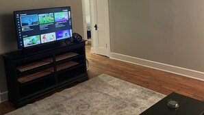 A living room with a flat-screen TV on a stand, a coffee table, and a patterned rug.