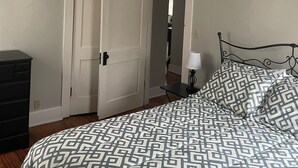 A bedroom with a bed, a dresser, a door, and a ceiling light.