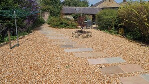 A gravel pathway leading to a stone house with a garden. - Alnside Cottage (Alnwick)