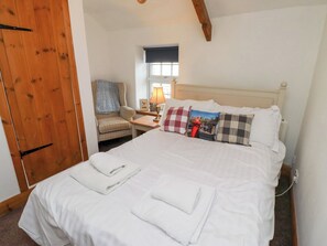 Cozy retreat with a large bed, wooden wardrobe, and comfortable chair.