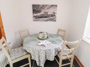 Enjoy meals in this cozy dining area with a round table for four, a teapot, and a framed photograph above.