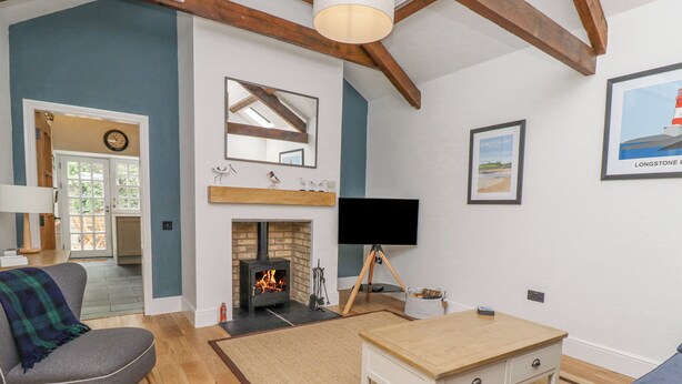 A living room with a fireplace, a television on a tripod, and a sofa. - Coral Cottage (Bamburgh)