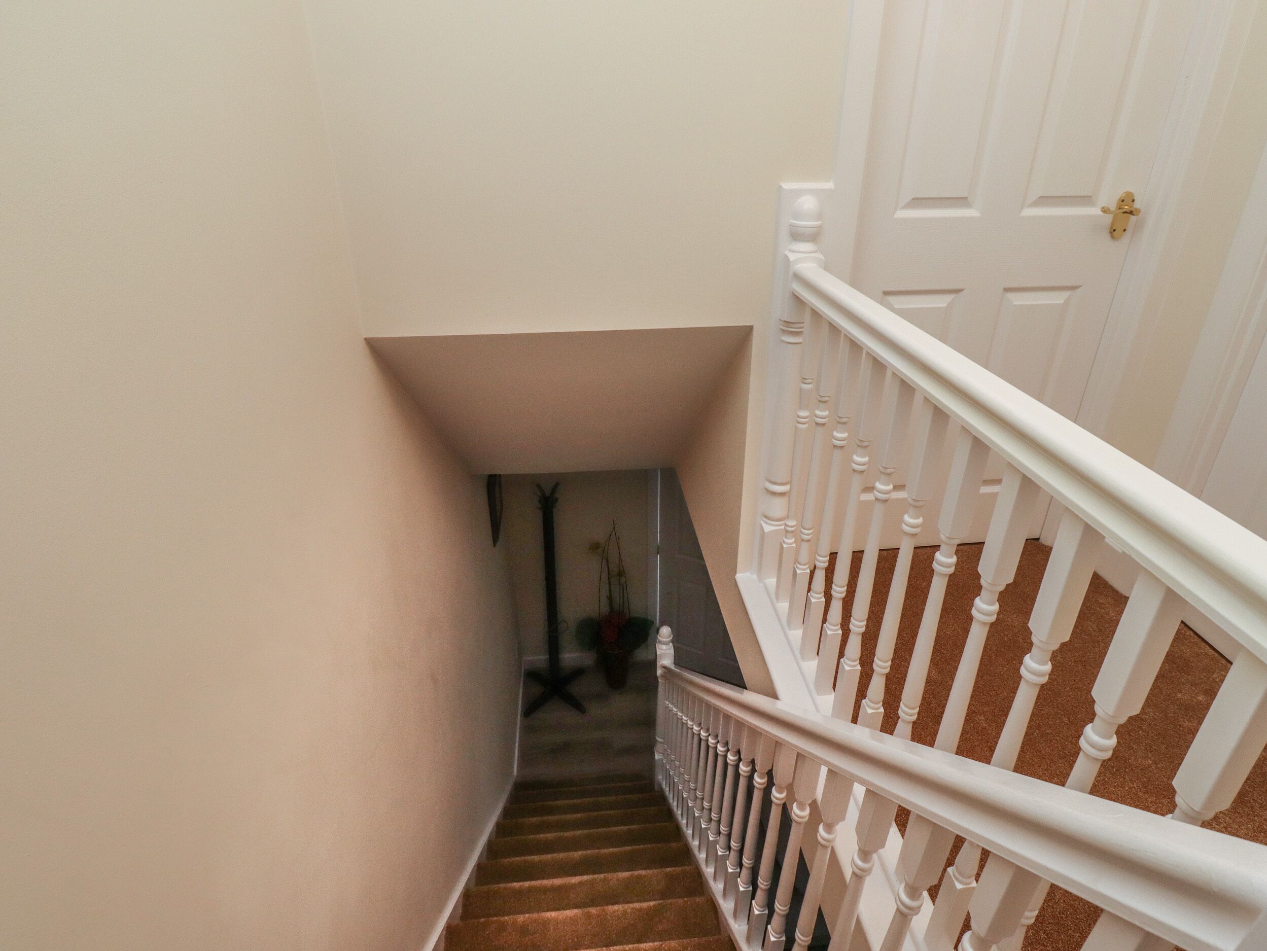 A staircase with white balusters and a door with a brass handle.