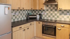 A kitchen with wooden cabinets, a stainless steel oven, and a tiled backsplash.