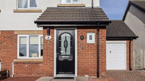 A residential house with a black front door, a brick facade, and a small porch.