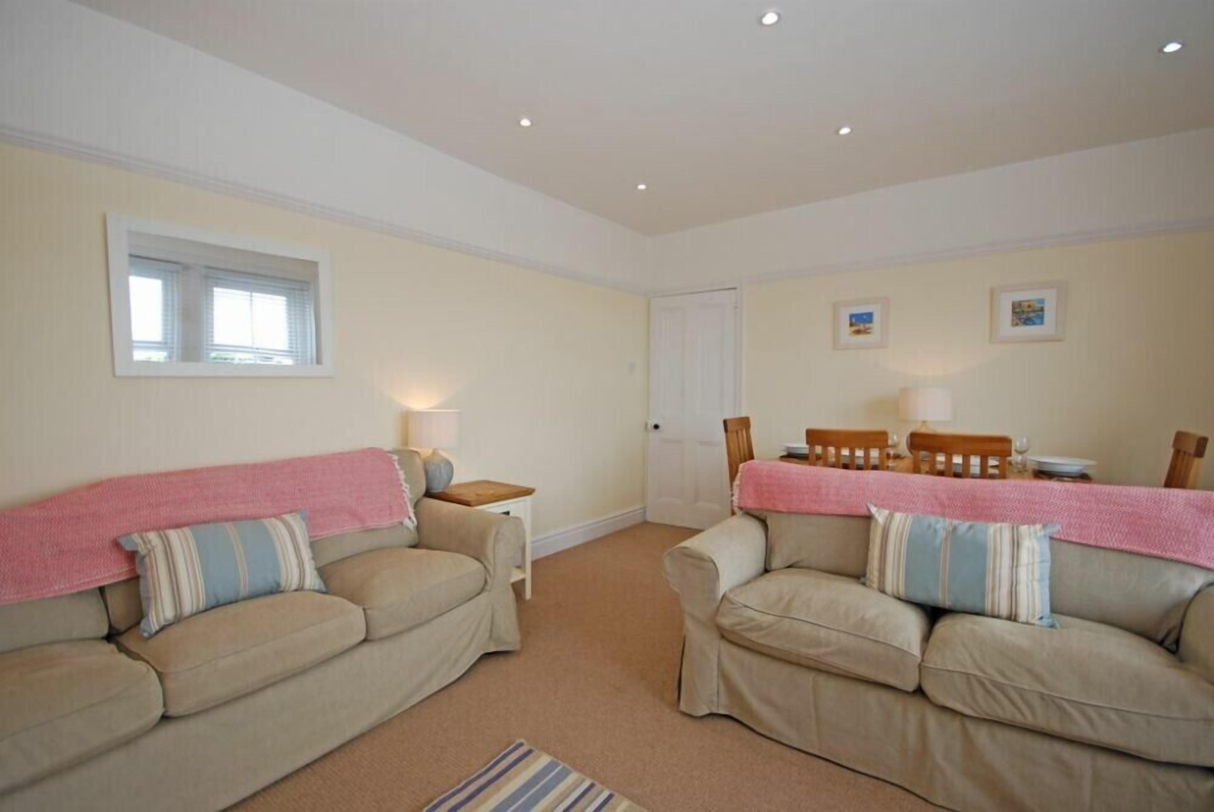 A cozy living room with two beige sofas, a small table, and a window.