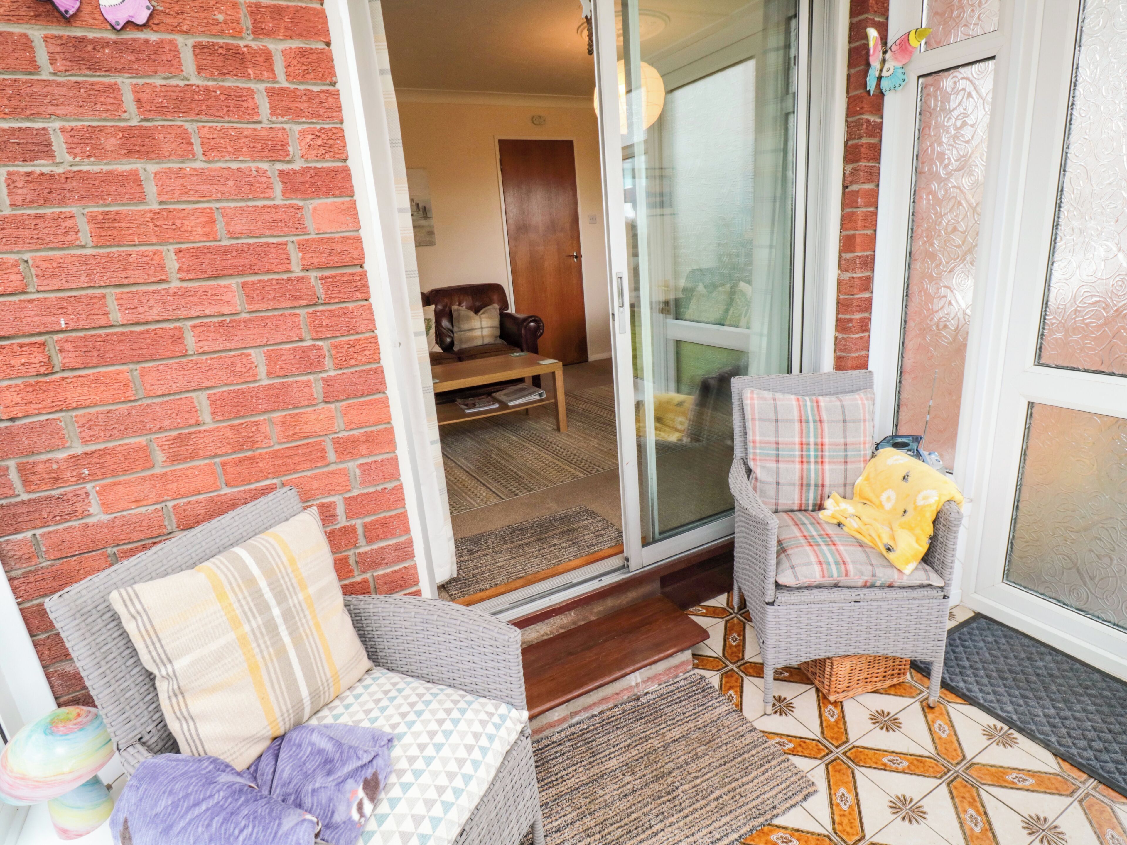 A cozy living area with a brick wall, a sliding glass door leading to a living room, and a patterned floor.