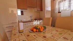 A kitchen with a dining table set for two, featuring a fruit plate and a bottle. - Peaceful Holiday House Senija (Vela Luka)