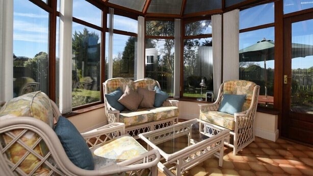 A conservatory with wicker furniture and large windows. - Armstrong Cottages No22 (Bamburgh)
