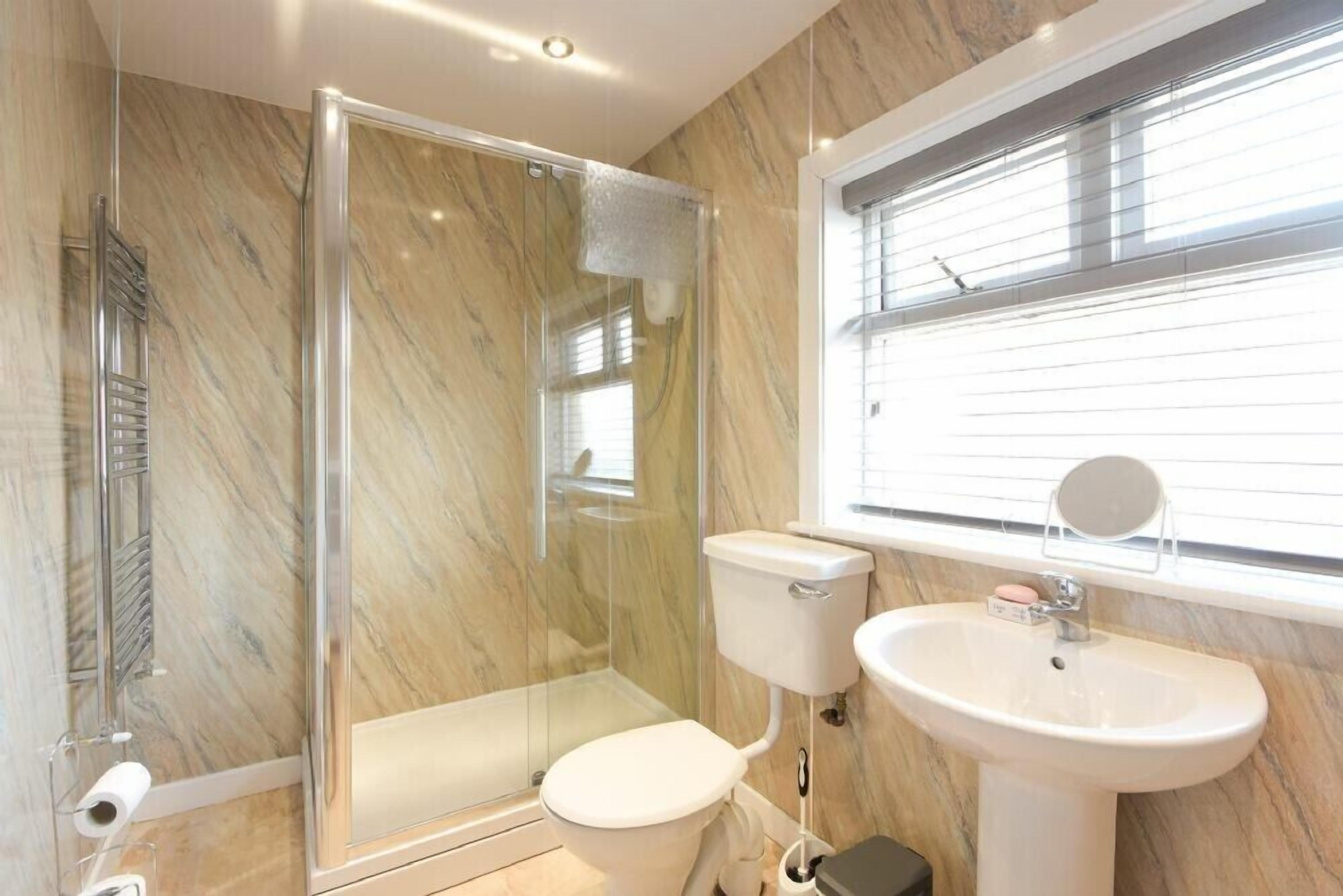 A bathroom with a glass-enclosed shower, a toilet, and a sink with a mirror.