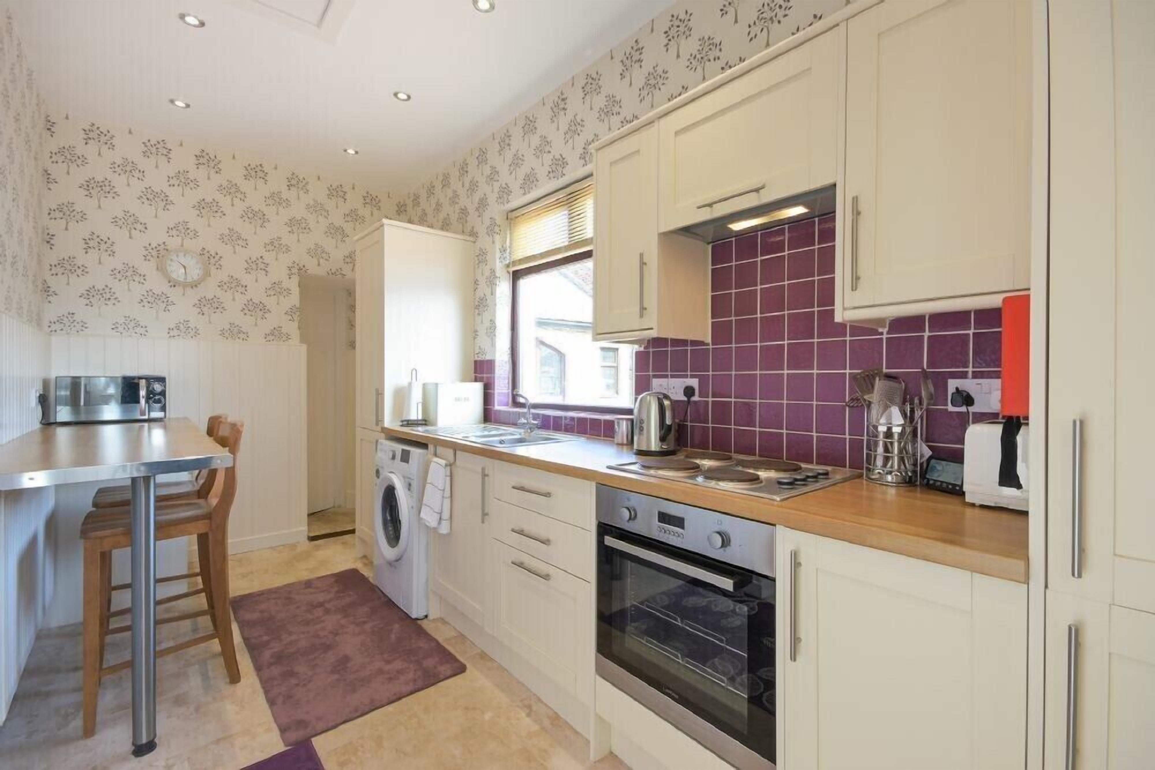 A compact kitchen with a washing machine, a built-in oven, and a sink.
