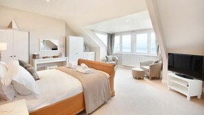 Une chambre moderne dotée d’un grand lit, d’une télévision et d’un coin salon offrant une vue sur l’extérieur.