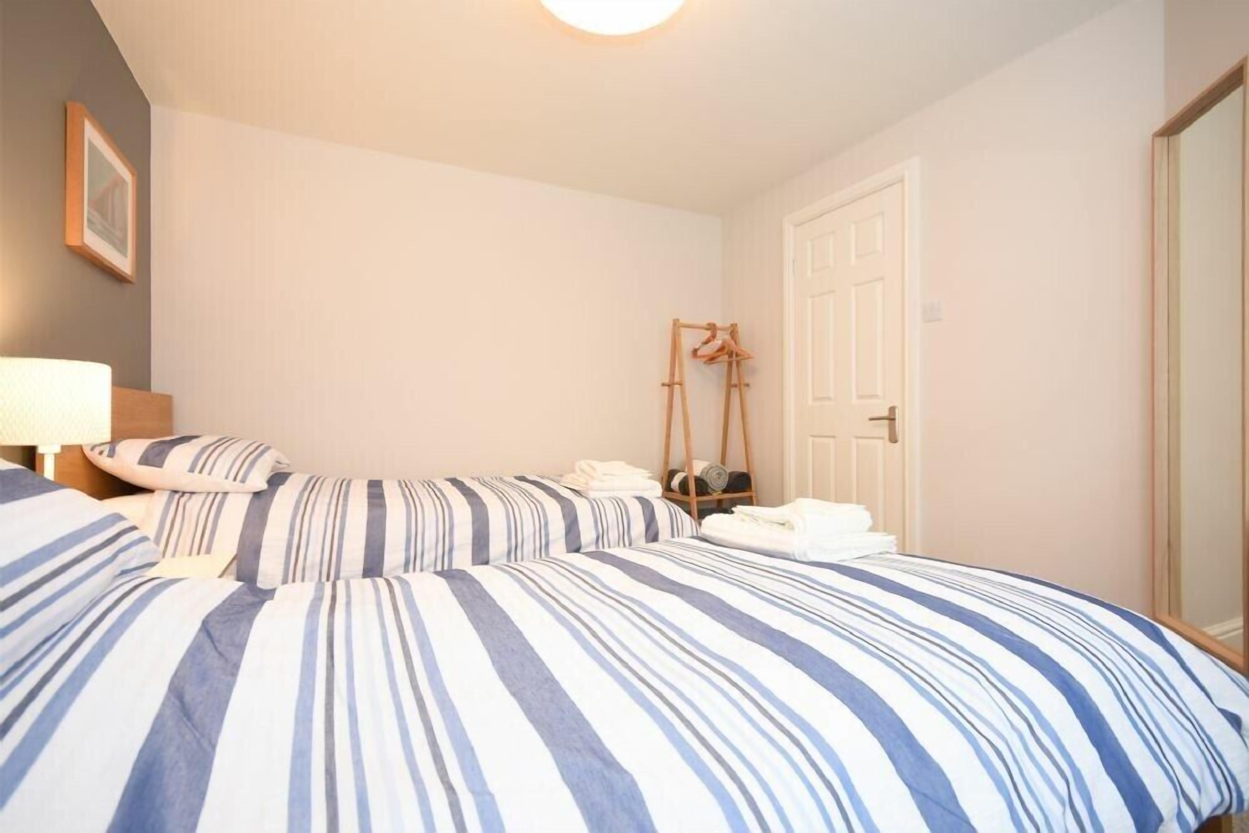 A bedroom with two beds, a wooden hanger, and a door.