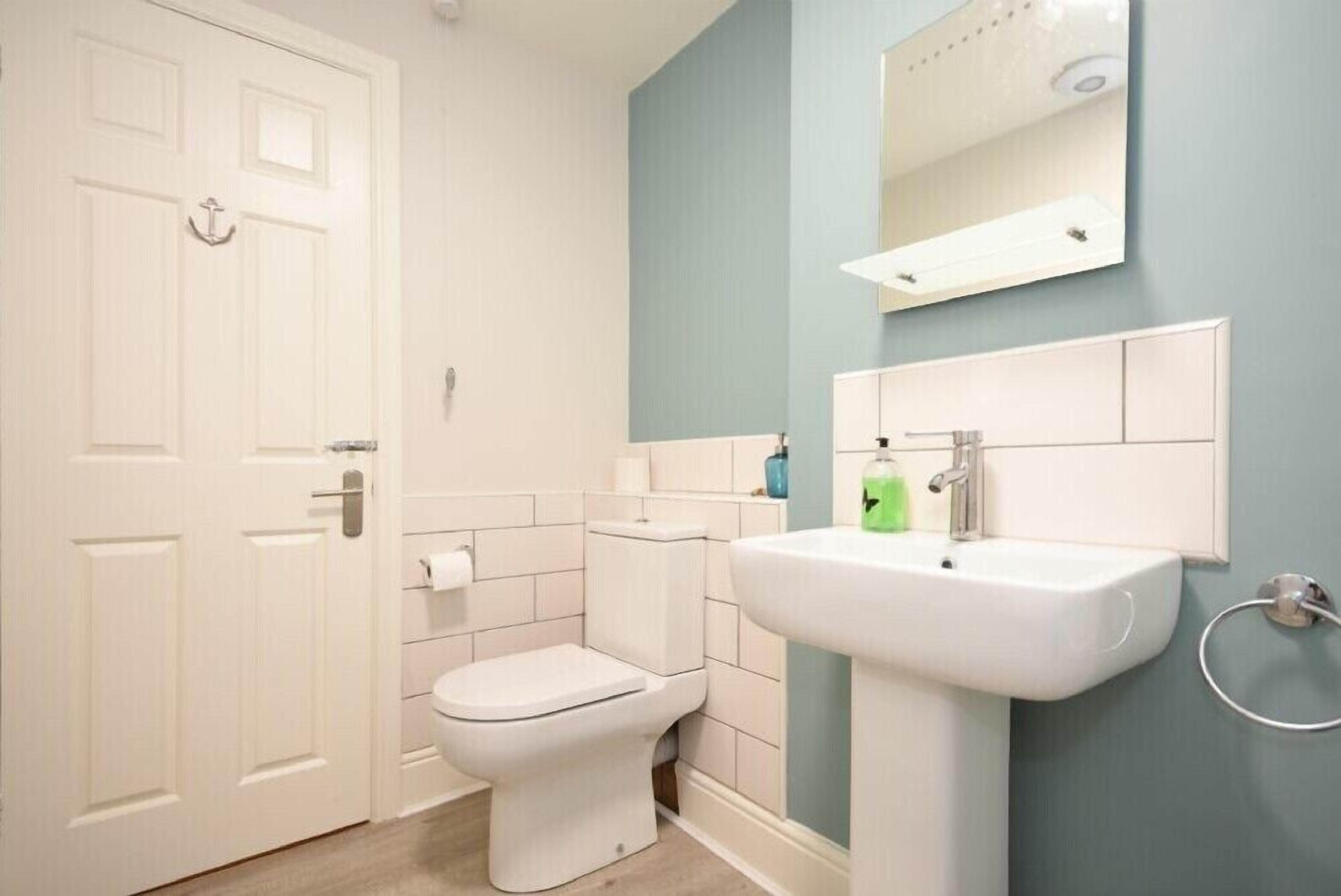 A bathroom with a toilet, sink, and a mirror above the sink.