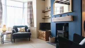 Una sala de estar acogedora con sofá, televisor, chimenea y estanterías decoradas.