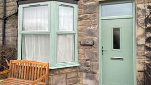 Un edificio de piedra con una puerta verde y una ventana con cortinas.