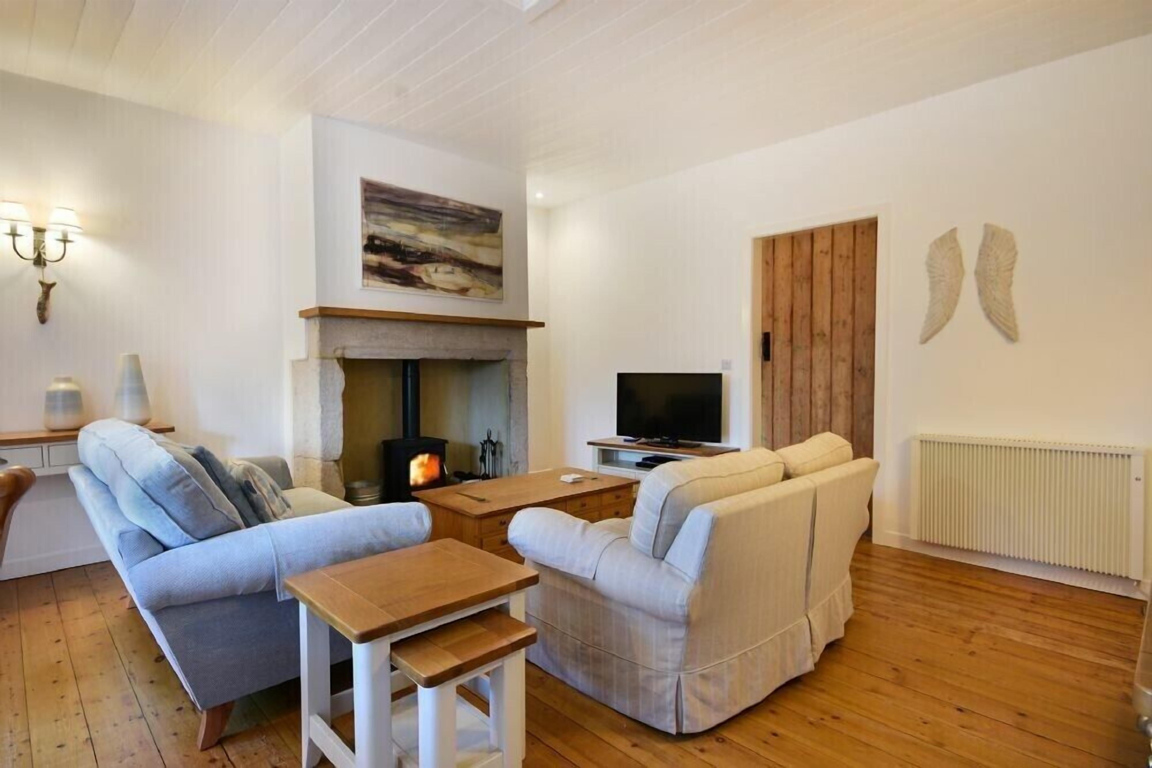 A cozy living room with a fireplace, a sofa, a TV, and a wooden floor.