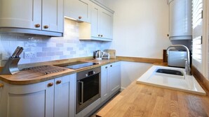 A modern kitchen with light-colored cabinets, a built-in oven, a sink, and a toaster.