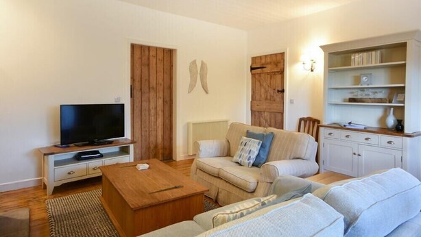 A cozy living room with a television, sofa, coffee table, and a bookshelf.