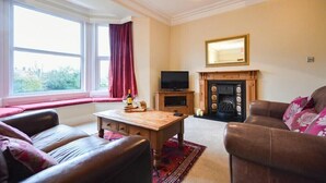 A living room with a fireplace, a television, and seating. - Sunnybrae (Alnwick)