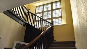 A staircase with a wooden handrail and black balusters, leading to a room with a large window and a framed picture on the wall. - Sunnybrae (Alnwick)