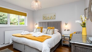Une chambre moderne avec un grand lit, des tables de chevet, un radiateur et une fenêtre donnant sur un paysage verdoyant.