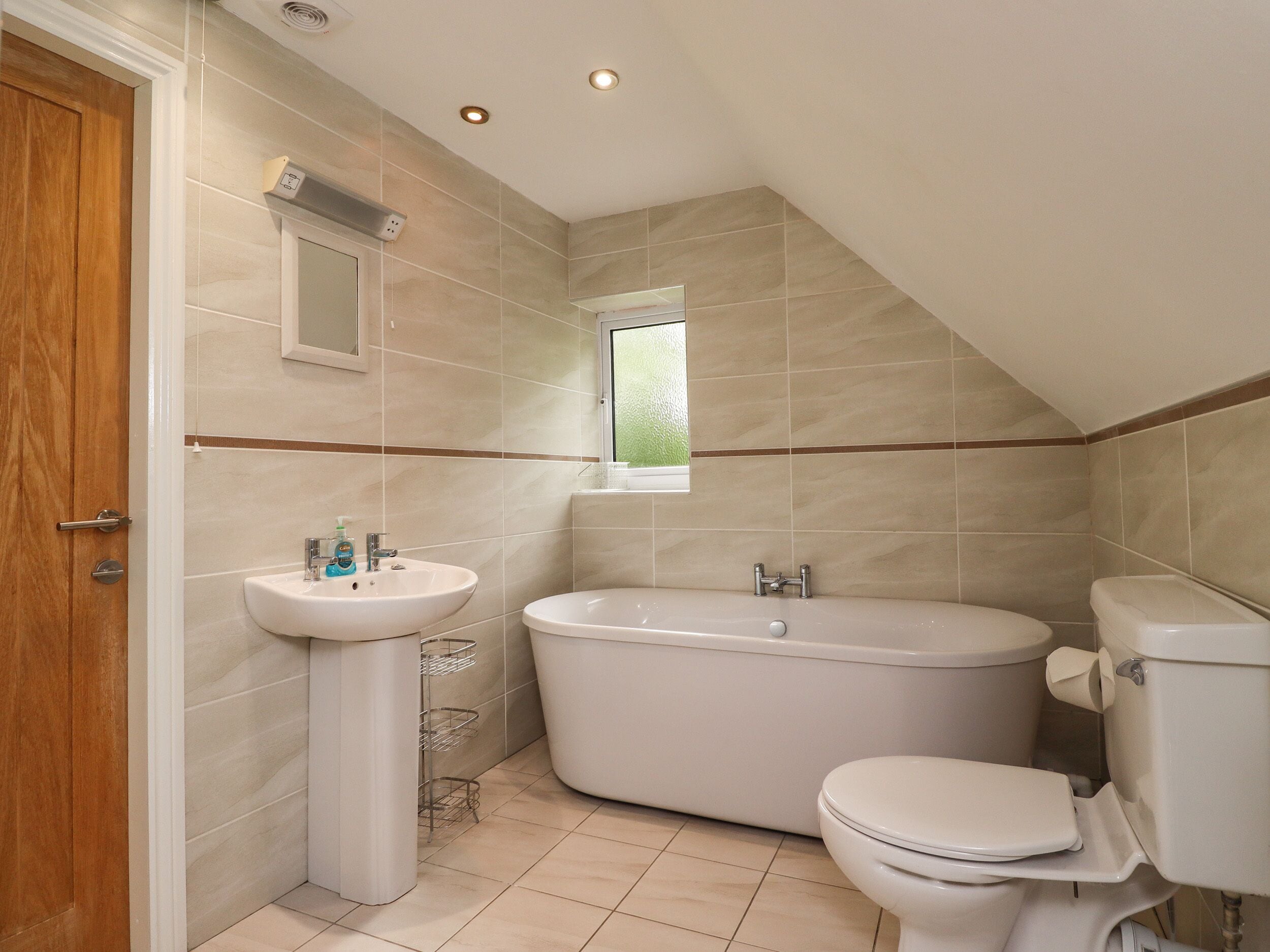 A bathroom with a freestanding bathtub, a toilet, and a pedestal sink.