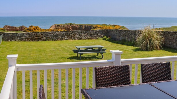 Un patio con mesa y sillas con vistas al mar.