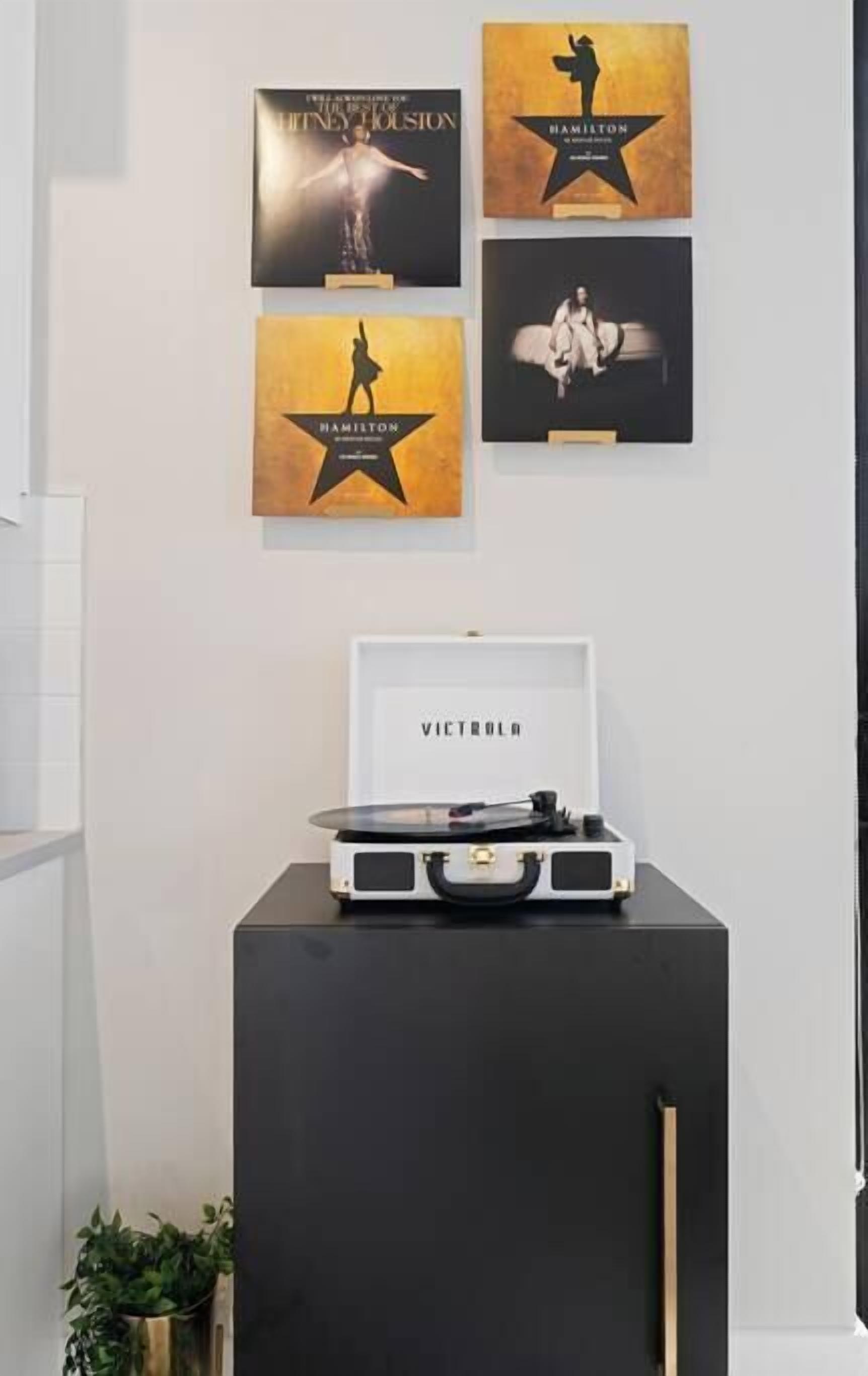 Un mur orné de tableaux encadrés, une platine vinyle et un haut-parleur.