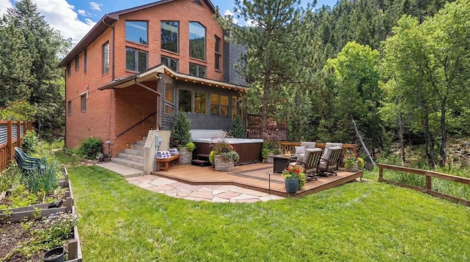 A two-story house with a deck, outdoor seating, and a hot tub.