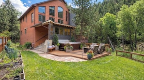 A two-story house with a deck, outdoor seating, and a hot tub. - Boulder Luxury Getaway | 7 acres /w River & Pond (Boulder)