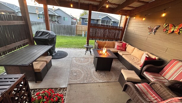 Een terras buiten met een vuurkorf, zitplaatsen en uitzicht op omliggende huizen.