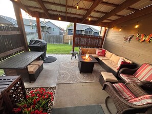An outdoor patio area with a fire pit, seating, and a view of neighboring houses.