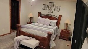 Een slaapkamer met een bed, een plafondventilator, een televisie en een klein tafeltje.
